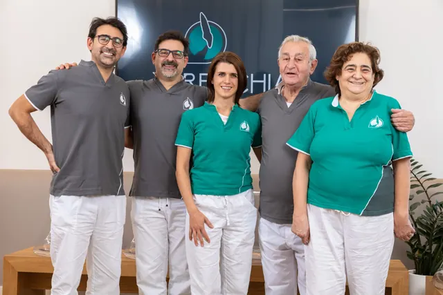 Sei medici dello studio in divisa davanti allo schermo col marchio: Michele, Piero e Andrea Recchia, Paola Chiaramonte e due colleghe