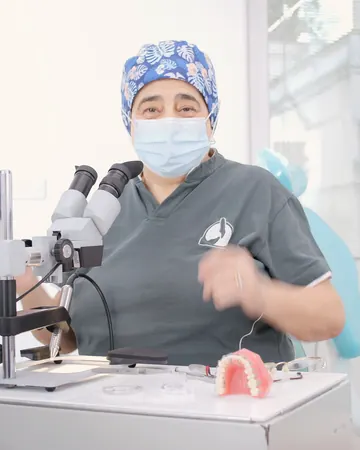 La Dott.ssa Paola Chiaramonte al microscopio, accanto a un modello di arcata con l'apparecchio