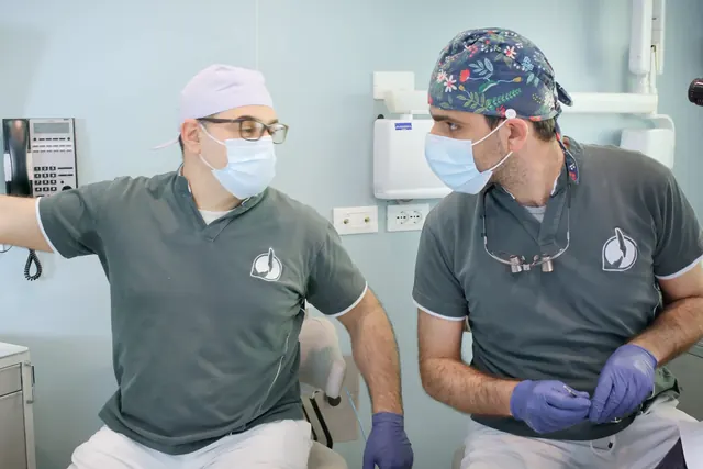 Due odontoiatri dello studio nella sala chirurgica: uno indica la radiografia, l'altro ascolta