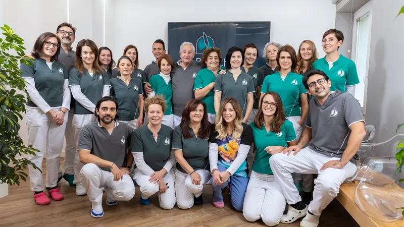 La squadra dello studio: ventidue persone nelle divise grigie e verde acqua, Andrea Recchia e Paola Chiaramonte al centro