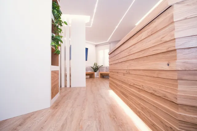 Il corridoio dello studio con la parete di listelli di rovere sfalsati e la luce radente in basso