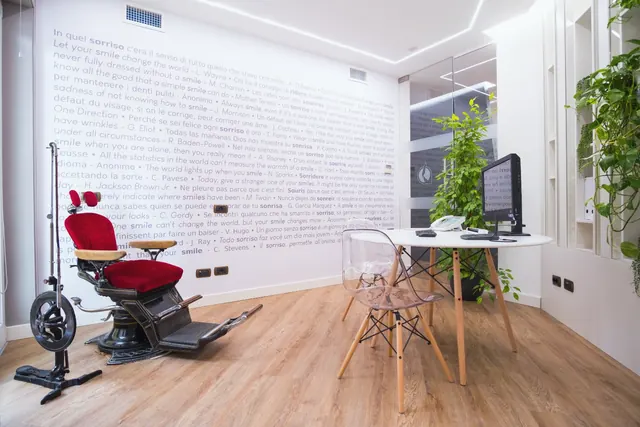Una poltrona da dentista d'epoca, in velluto rosso, in una stanza bianca dello studio con le frasi sul sorriso scritte alla parete