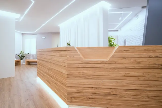 La reception dello studio in Via Mameli: un bancone di listelli di rovere con un intaglio a V, linee di luce sul soffitto